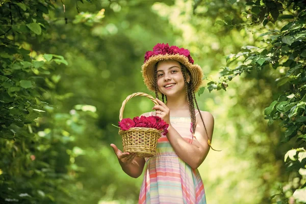 Heureuse enfant fille en chapeau de paille avec des fleurs roses en été nature, printemps — Photo