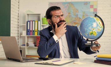 Sakallı coğrafyacı sınıfında haritayla çalışıyor. Sınava hazırlan. Coğrafya dersi veren üniversite hocası. Okula dönüyorum. gayri resmi eğitim. Küreye bakan gerçek bir yetişkin öğretmen.