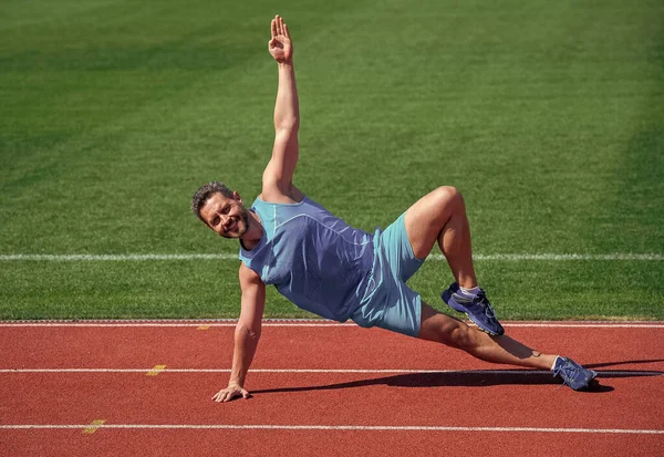 Happy and sporty. male athlete do morning exercise. warm up workout. sportsman flex muscles outdoor. muscular guy do stretching. man in yoga pose. sports and healthy lifestyle routine. sport success
