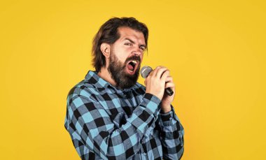 Ses egzersizi. Müzik. Olgun bir adam şarkı söyler. Ses sınıfları. Müzik tarzı. Sakallı adam mikrofonda şarkı söylüyor. Karaoke kulübündeki vahşi adam. Erkek mikrofonla şarkı söylüyor. Yakışıklı hippi partideymiş.