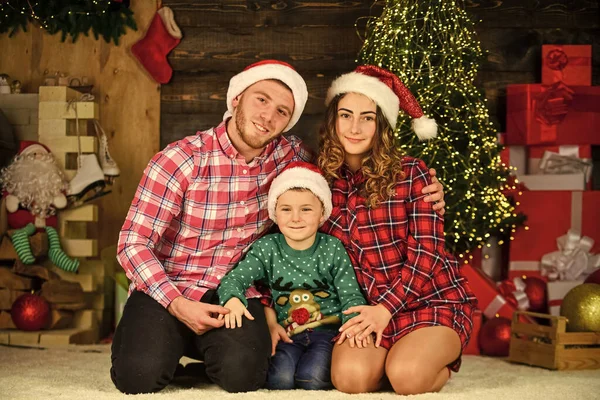 Nos encanta la Navidad. hijo con padres en sombrero de santa. El niño pequeño ama a mamá y papá. amor pasar vacaciones juntos. divirtiéndose. Año Nuevo en casa. retrato de navidad familiar. familia feliz celebrar la Navidad —  Fotos de Stock