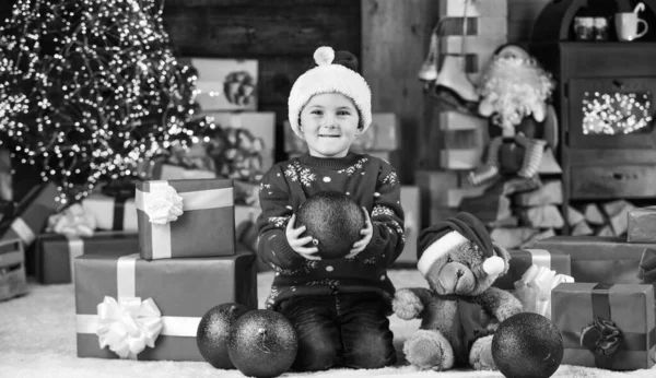 Mutlu çocuk Noel Baba şapkası. Oğlum kış tatilini kutlamaya hazır. Küçük çocuk heyecanla hediye bekliyor. Çocuk dekoratif balo düzenliyor. Noel için oyuncak hediye getirdim. Mutlu noeller. Mutlu yıllar. — Stok fotoğraf
