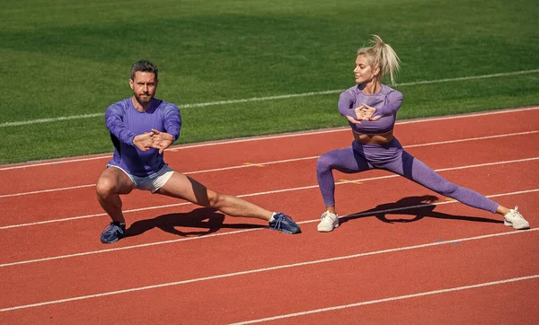 Fitness homem esporte e mulher aquecimento e alongamento juntos na pista de corrida estádio ao ar livre vestindo sportswear, treinador — Fotografia de Stock