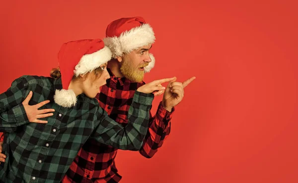 Compras familiares. Festa de Natal. Ideia para se divertir. Bom humor. Alegria de inverno. Casal apaixonado apontando espaço de cópia. Olha para isto. Estilo Papai Noel. Tempo de Natal. Homem e mulher Natal celebração feriado — Fotografia de Stock