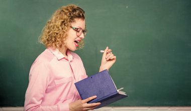 Karatahtanın önündeki kadın öğretmen. Bilgiye karşı tutkulu. Pedagog kitabı tutuyor ve bilgiyi açıklıyor. Eğitim konsepti. Öğretmen zor konuyu açıkla. Öğrencilerin en iyi öğretmeni.