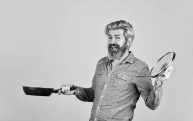 Sağlıklı yemek pişirme. Kocası mutfakta. Yemek pişirme konsepti. Tavayı tut. En iyi kalite Sakallı aşçı portresi ve mutfak aletleri. Sakallı adam, yemek tepsisini tut. Mutfakta yemek pişir.