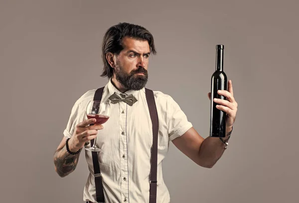 Leverans av vin. Dricka vinglas. Skäggig man i hängslen dricker rött vin. elegant affärsman bära fluga för formella evenemang. sommelier provsmakning alkohol. Bartendern. snygg manlig bartender — Stockfoto