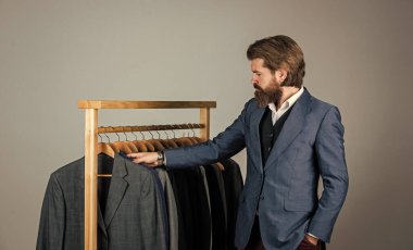Özel dikim takım elbiseli bir adam pahalı bir smokin giyiyor. Butikte erkek kıyafetleri. Takım elbiseli adam. Atölyesindeki terzi. Klasik kostümlü yakışıklı sakallı moda adamı.