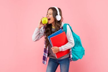 Okul çantasıyla kulaklıkla müzik dinleyen mutlu çocuk..