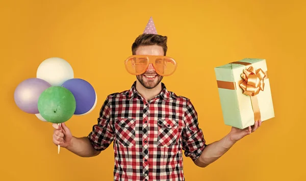 Ung stilig man i rutig skjorta hålla fest ballonger och presentförpackning, födelsedag — Stockfoto