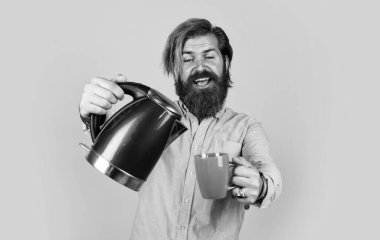 Bu senin için. Sakallı adam kırmızı elektrikli su ısıtıcısı kullanıyor. Erkek ev idaresi konsepti. Sıcak suya ihtiyacım var. Adam çay ya da kahve içecek. Bıyıklı ve sakallı vahşi bir adam. elektrikli ev aygıtı