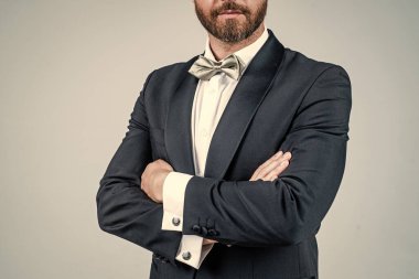 Tıraşsız sakallı, kendine güvenen damat şık bir smokin ve papyon giyer.