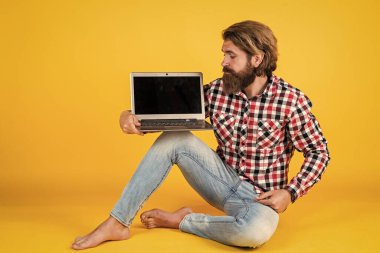 Vahşi sakallı adam kareli gömlek giyiyor sakalı ve bıyığı gür dizüstü bilgisayarında çalışıyor, yeni teknoloji.