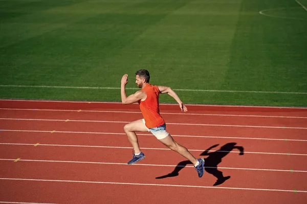 Atletico uomo muscoloso che corre in pista allo stadio all'aperto, finitura — Foto Stock