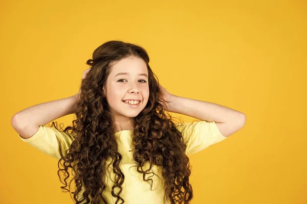 Rizos saludables. Peinado fácil. Artículos de belleza. Desenreda perfectamente el cabello rizado. Chica bonita pelo rizado fondo amarillo. Cabello largo. Peluquería. Adorable niño pequeño. Hermosa modelo poco — Foto de Stock