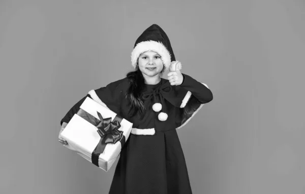 Paczka prezentów. Ukochane marzenia. Dzień boksu. Mała urocza dziewczyna Mikołaj kapelusz trzymać pudełko prezentów. Dzieciak trzymać obecne pole czerwone tło. Wesołych Świąt i wesołych świąt. Zimowe wakacje. Świąteczne zakupy upominkowe — Zdjęcie stockowe