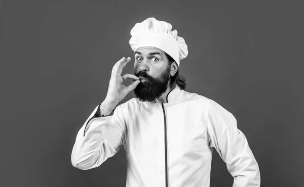 Захоплення. красивий чоловік з бородою і вусами готує їжу. професійний ресторан готує випічку. кваліфікований пекар використовує кухонне начиння для приготування їжі. чоловічий шеф-кухар в капелюсі готує здорову їжу — стокове фото