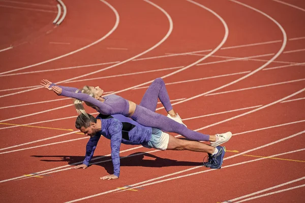 Αθλητισμός fitness άνθρωπος και γυναίκα κατάρτισης μαζί σταθεί σε σανίδα και να ωθήσει προς τα επάνω σε υπαίθρια αγωνιστική στάδιο φορώντας αθλητικά ρούχα, προπόνηση αθλητισμού — Φωτογραφία Αρχείου