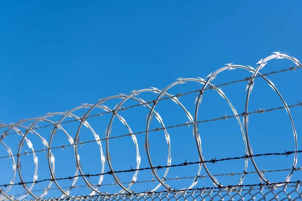 Barbwire prison wall with barbed wire fence coiled razor wire perimeter fence, barb Stock Photo