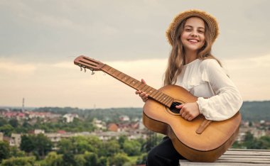 Moda görünümlü kız akustik gitar ve müzik çalıyor.