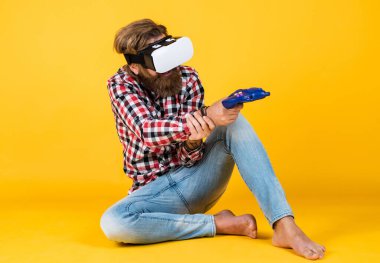Oyunu oyna. Adam VR kulaklık takarak tecrübe kazanıyor. Sakallı hippi modern teknoloji kullanır. Oyun konsolu. Sanal gerçeklik gözlüklü bir adam. Geleceğin teknolojisi. Görsel gerçeklik kavramı