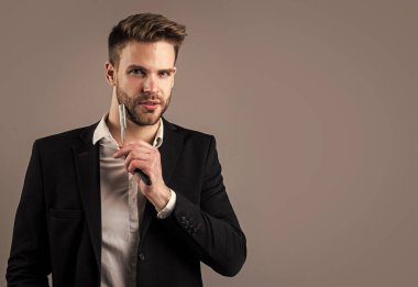 Takım elbiseli genç yakışıklı adam jilet tutuyor. Erkek berber ustası. İş görünümlü sakallı bir adam. moda ve güzellik. Berber dükkanı konsepti. Erkek saç şekillendirme ve tımar