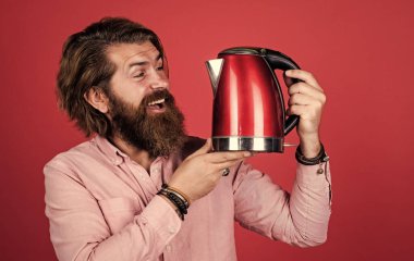 Sıcak içecek iç. Mutfak gereçlerini sunuyorum. İyi kalite. Sakallı, çay içen olgun bir hippi. Elektrikli su ısıtıcısı olan vahşi bir adam. Gününü ısıt. Sakallı adam. Çok hoşuma gitti.