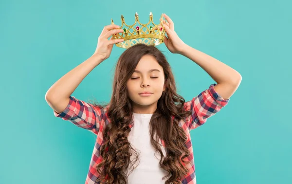 Sonhador adolescente menina com cabelo encaracolado desgaste coroa no fundo azul, presunçoso — Fotografia de Stock