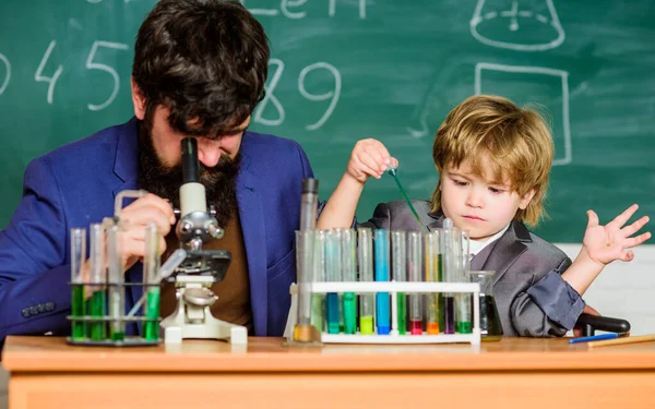 Mikroskop. Skäggig manslärare med liten pojke. laboratorieforskning och utveckling. Kemiska bägare experiment. far och son barn i skolan. Laboratorieprovrör och -kolvar med färgad vätska — Stockfoto