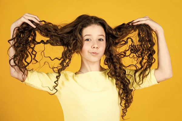 Long hair. Hairdresser salon. Adorable small child. Beautiful little model. Healthy curls. Easy hairdo. Beauty supplies. Perfectly untangle curly hair. Pretty girl curly hair yellow background — Stock Photo, Image