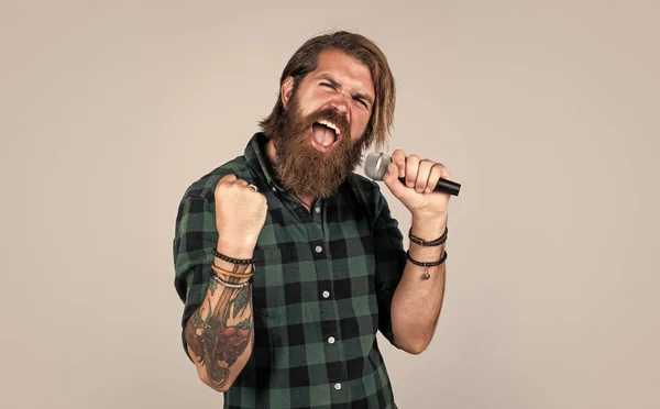 Arte. Um tipo com barba a cantar no microfone. confiança e carisma no palco. Homem barbudo usando camisa quadriculada. Música rock. cantor de karaoke masculino. maduro carismático masculino vocalista — Fotografia de Stock