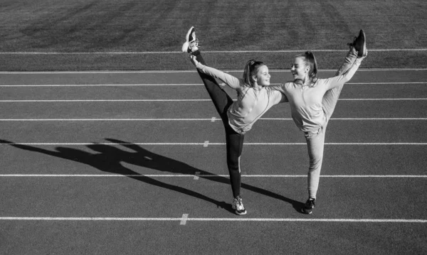 Udržuje ty svaly pružné. dospívající dívky se zahřívají na stadionu. děti ve sportovním oblečení se protahují. děti cvičí. zdravé dětství. cvičení na čerstvém vzduchu venku. sebevědomí flexibilní gymnastky — Stock fotografie