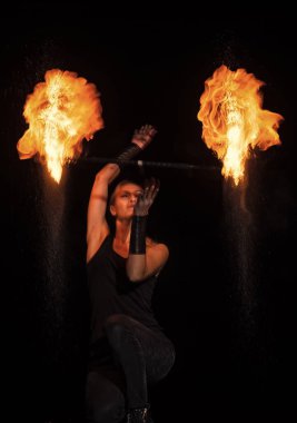 Yanan arzular. Şehvetli bir kadın karanlıkta alevli bir değnek çeviriyor. Ateş performansı.