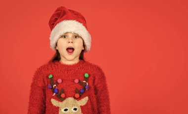 Duygusal yüz ifadesi. Mutlu bir çocukluk. Noel 'e kadar günleri sayıyorum. Noel partisi. Duygularını zapt edemiyorsun. Noel davetiyesi. Sevimli kız Noel Baba şapkası takıyor kırmızı arka plan