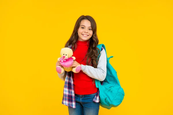 Glad barn casual stil med ryggsäck och leksak på gul bakgrund, skola — Stockfoto