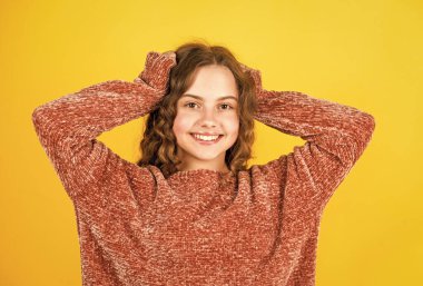 İpeksi saçların tadını çıkar. Güzel, küçük bir model. Sağlıklı bukleler. Kolay saç modeli. Kuaför salonu. Sevimli küçük çocuk. Güzellik malzemeleri. Mükemmel kıvırcık saçlar. Güzel kız kıvırcık saçlı sarı arka plan