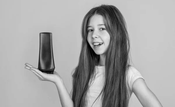 Cheerful kid girl with long straight hair hold conditioner shampoo or gel bottle, bath — Stock Photo, Image