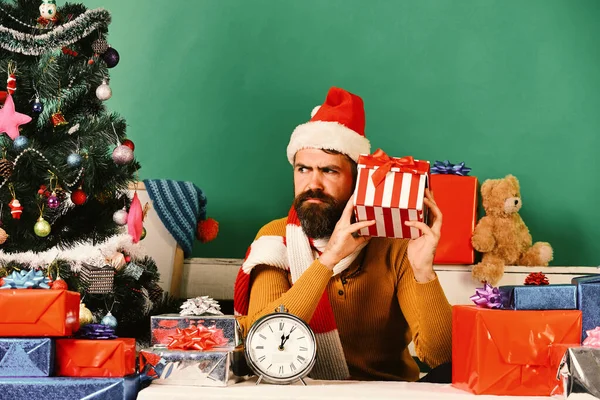 Le Père Noël tient une boîte cadeau. Homme avec barbe et visage curieux — Photo