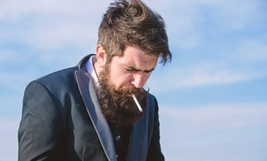 Sigara aydınlatıyor. İş adamı gökyüzüne karşı. Gelecekteki başarısı. Erkek resmi moda. Sakallı adam sigara içiyorum. duman. Bıyıklı acımasız beyaz hippi. Olgun hipster sakallı