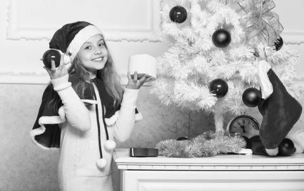 Çocuk kırmızı ile Noel ağacı süsleme süsler topları. Aziz tatil aktivitesi. Santa şapka Noel ağacı süsleme evlat. Aile geleneği kavramı. Kız çocuk dekorasyon Noel ağacı — Stok fotoğraf