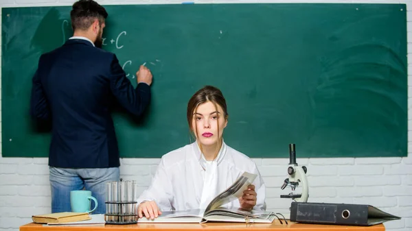 Cours de chimie. Jolie prof de chimie enseigner étudiant en classe. Homme barbu répondant à la chimie au tableau devant le professeur. L'éducation. Etude scolaire — Photo