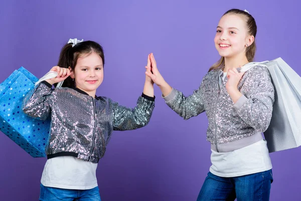 Omdat imago alles is. Winkelen en kopen. Zwarte vrijdag. Verkoop en korting. Winkeldag. Kinderen pakketjes. Kindermode. Meisjes zussen vrienden met boodschappentassen violet achtergrond — Stockfoto