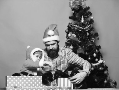 Noel Baba şapkalı adam ve çocuk yavru köpeklerle oynuyorlar.