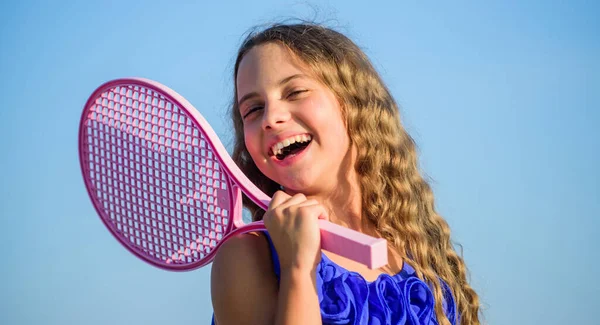 Ocio de verano. Juego de deportes. Chico alegre juguetón. Feliz infancia. Positivo. Bebé emocional. Vida activa. Niño jugar tenis azul cielo fondo. Chico deportivo. Niña pequeña con raqueta de tenis rosa — Foto de Stock