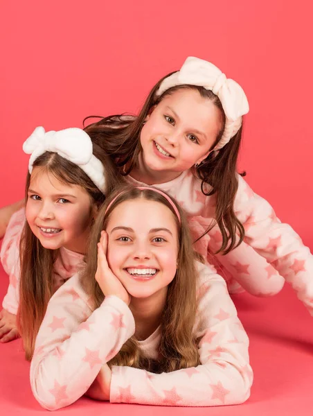 Crianças felizes deitado perto um do outro fundo rosa. Retrato de infância feliz em pijama — Fotografia de Stock