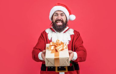 Sakallı Noel Baba kutusunu şapkada tutarken gülümsüyor ve yeni yıl partisini kutluyor ve kışın Noel tatilinde hediyeler alıyor, hediyeleri paylaşıyor.