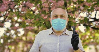 Yetenekli doktor. Solunum maskesi ve eldiven giymiş yaşlı bir adam. Parkta sakura çiçeği ağacı. Koronavirüs kovid 19. Bahar keyfi. Yasak Sakura Parkı. Park koronavirüs nedeniyle karantinaya alınmıştır.