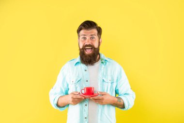 Sarı arka planda sakallı neşeli hippi kahve fincanı tutuyor, sabah