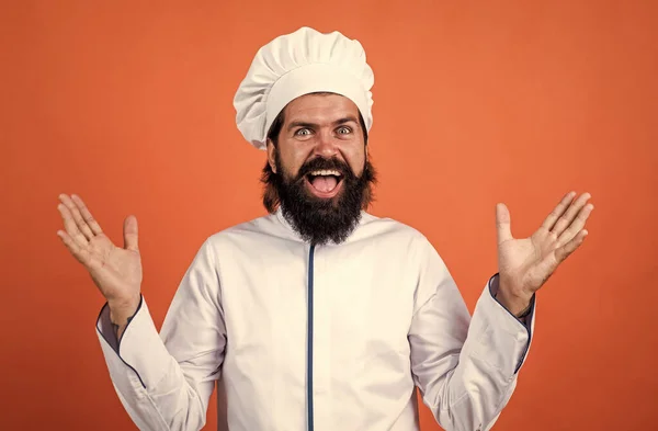 Gelukkig zelfverzekerde chef-kok man met baard en snor in kok uniform op oranje achtergrond, geluk — Stockfoto