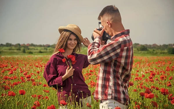Pareja enamorada de hombre y mujer haciendo foto en la cámara en el campo de flores de amapola de verano, fotografiando — Foto de Stock